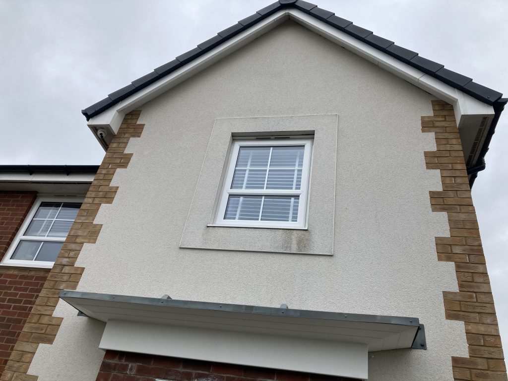 Rendered home in Melksham showing early signs of algae colonisation around window sills.